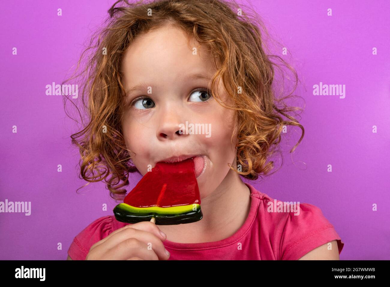 child enjoying watermelon lollipop, pretty little girl licking candy. Stock Photo