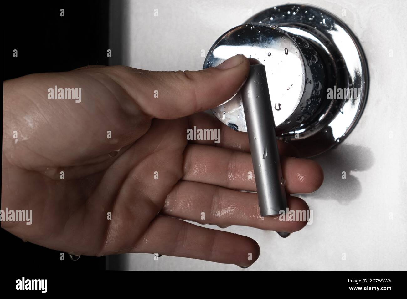 hand switches shower mixer for switching between hot and cold water. Stock Photo