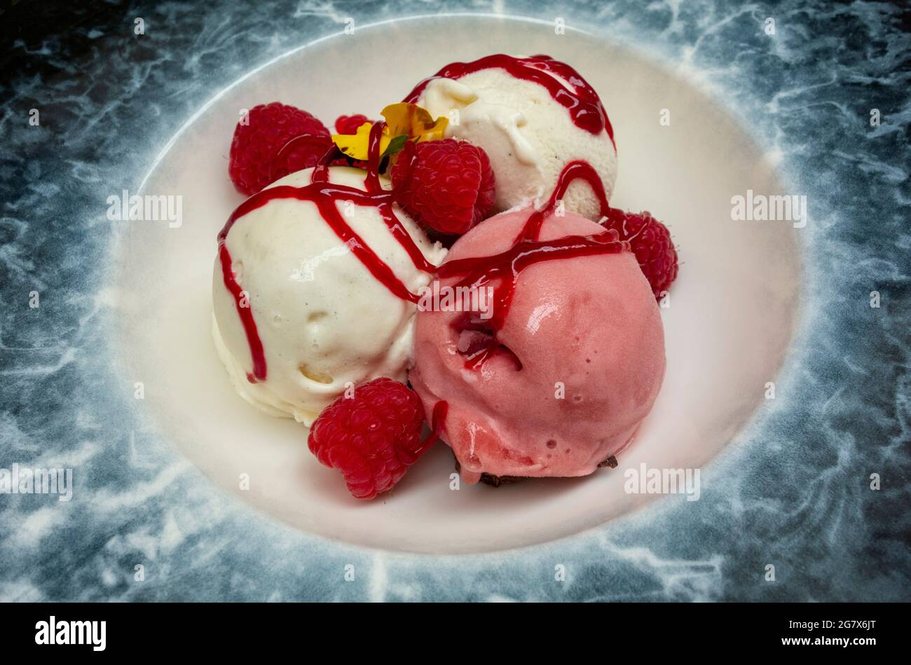Strawberry and vanilla ice cream with raspberries and raspberry coulis hires stock photography