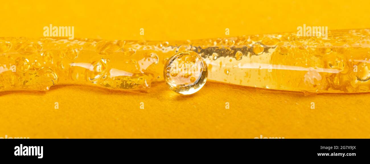 pure clear marijuana wax on yellow background, cannabis dab texture