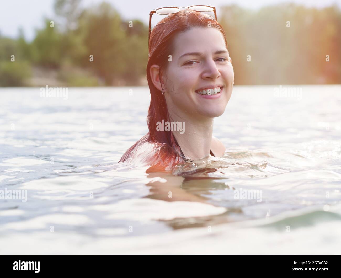 Portrait of a Young Woman with Red Hair Swimming in Lake Stock Photo