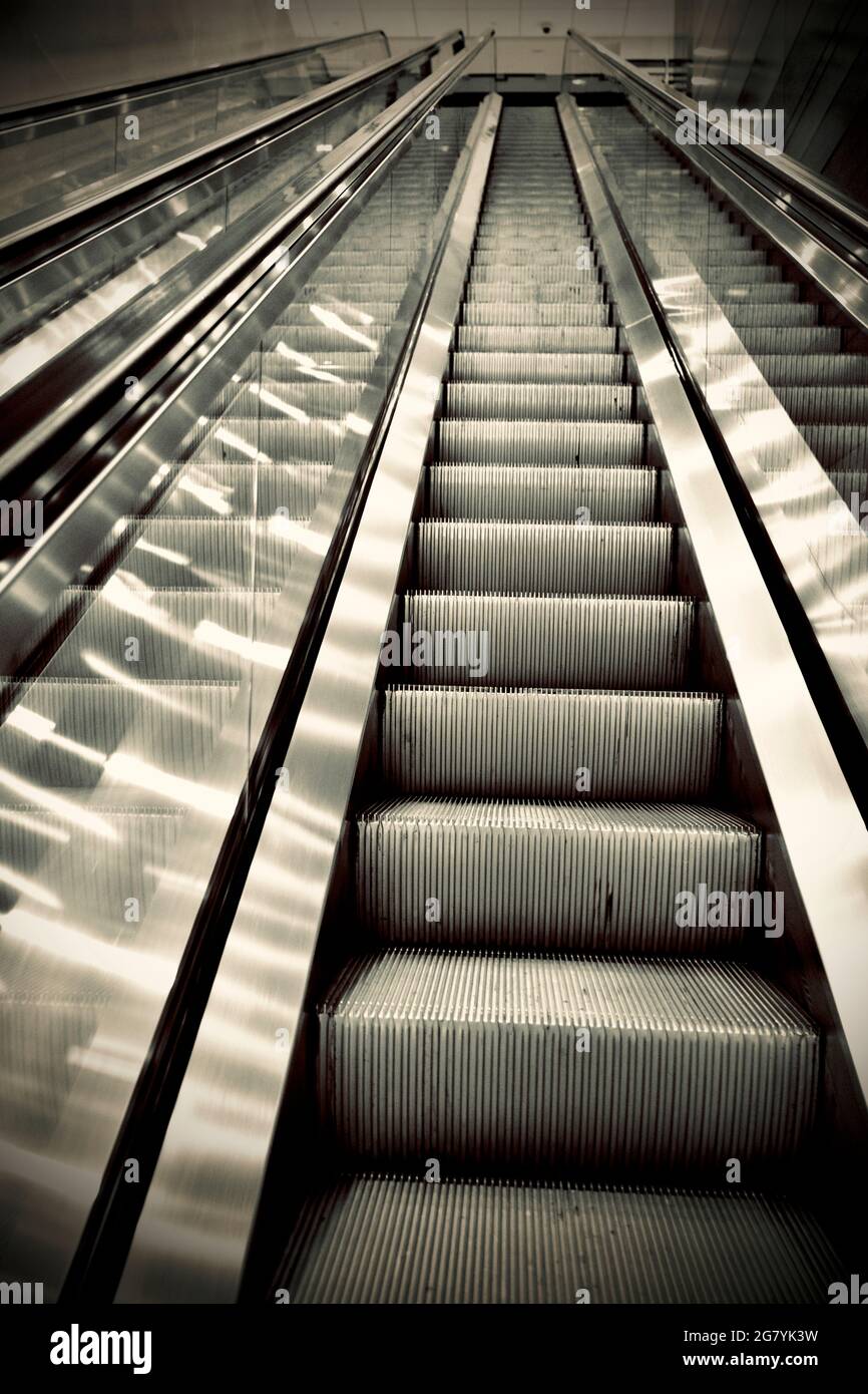 Escalator in office building empty of any people, strong perspective lines, looking up. Stock Photo