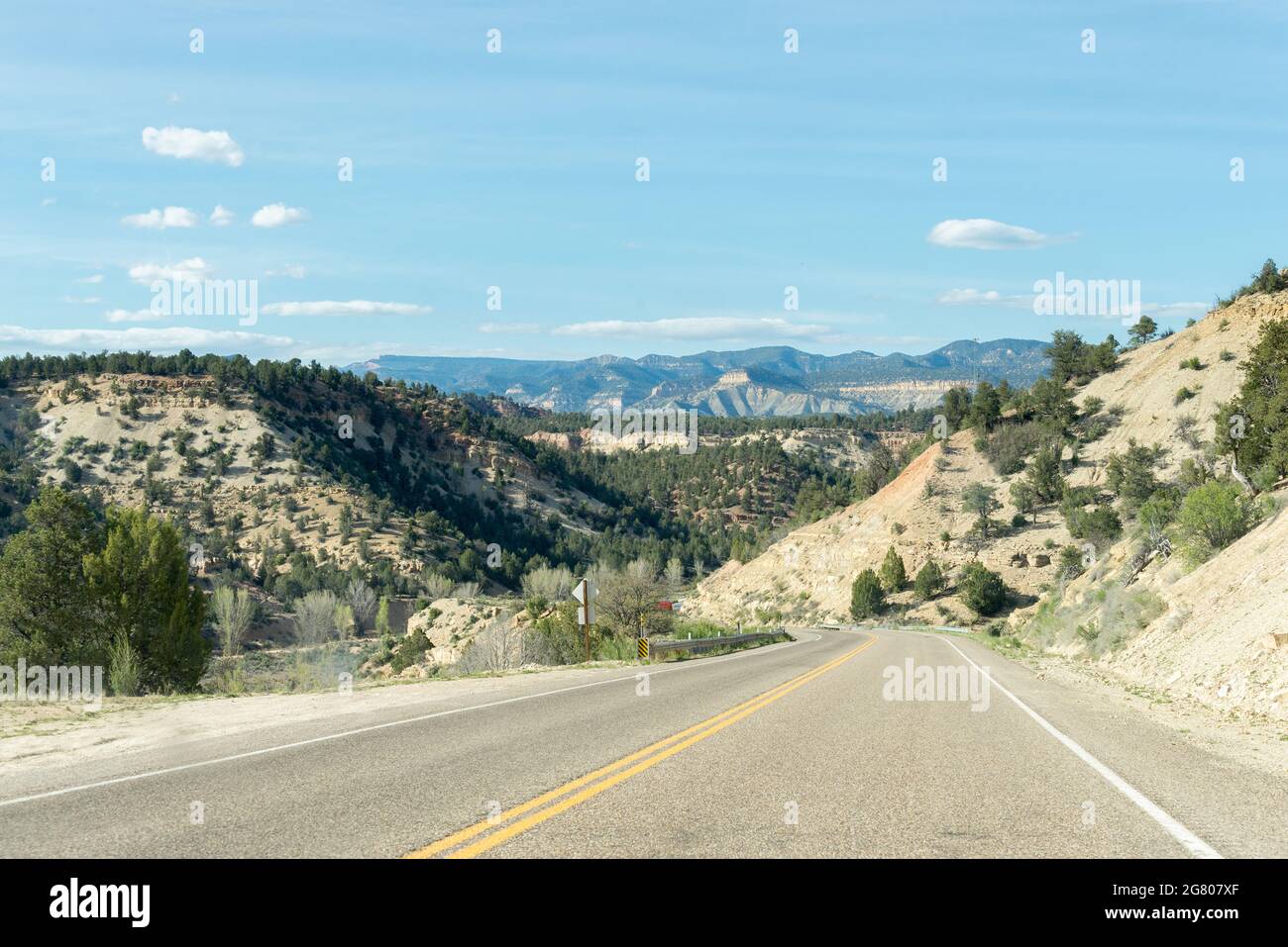 Lonely road between mountain ridges with some trees on each side of the ...