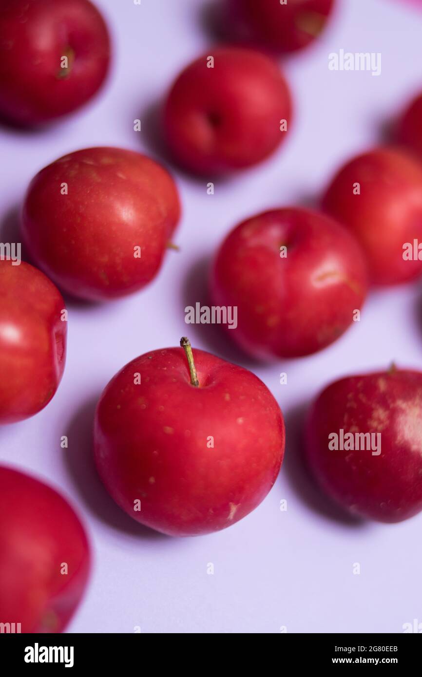 Close up of some fresh red plums on a colorful purple surface Stock Photo