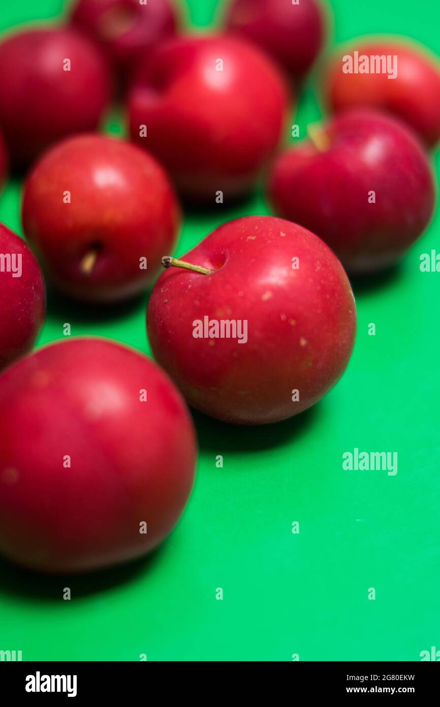 Close up of some fresh red plums on a colorful green surface Stock Photo