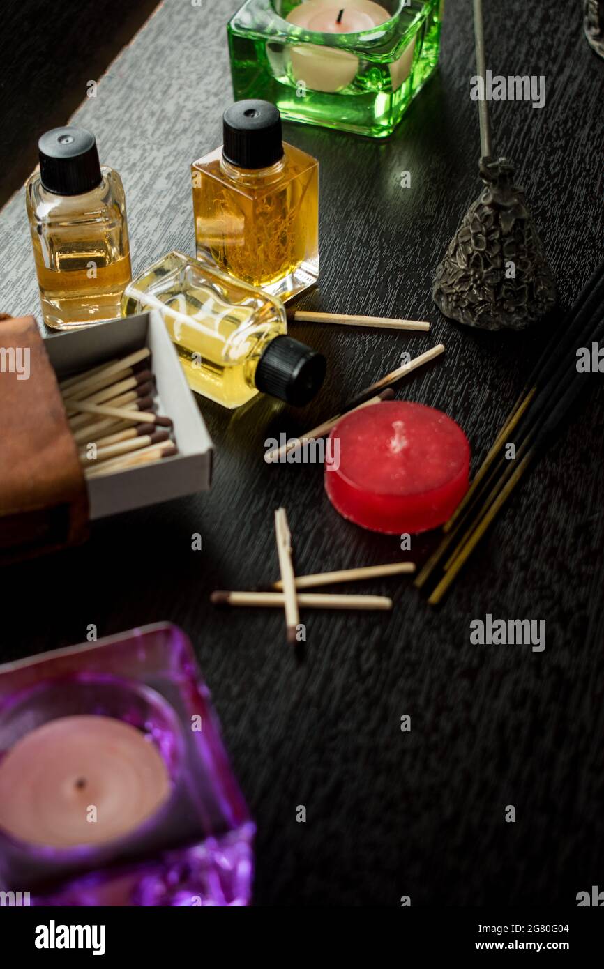 Some wooden matches in a matches box, candles and some glass flovering bottles on a black wooden table Stock Photo