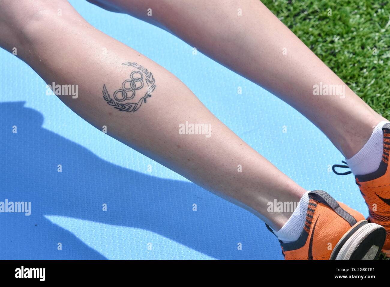 The Olympic tattoo seen on a girl's leg while she's doing exercises at the  open air, image size:1300x956