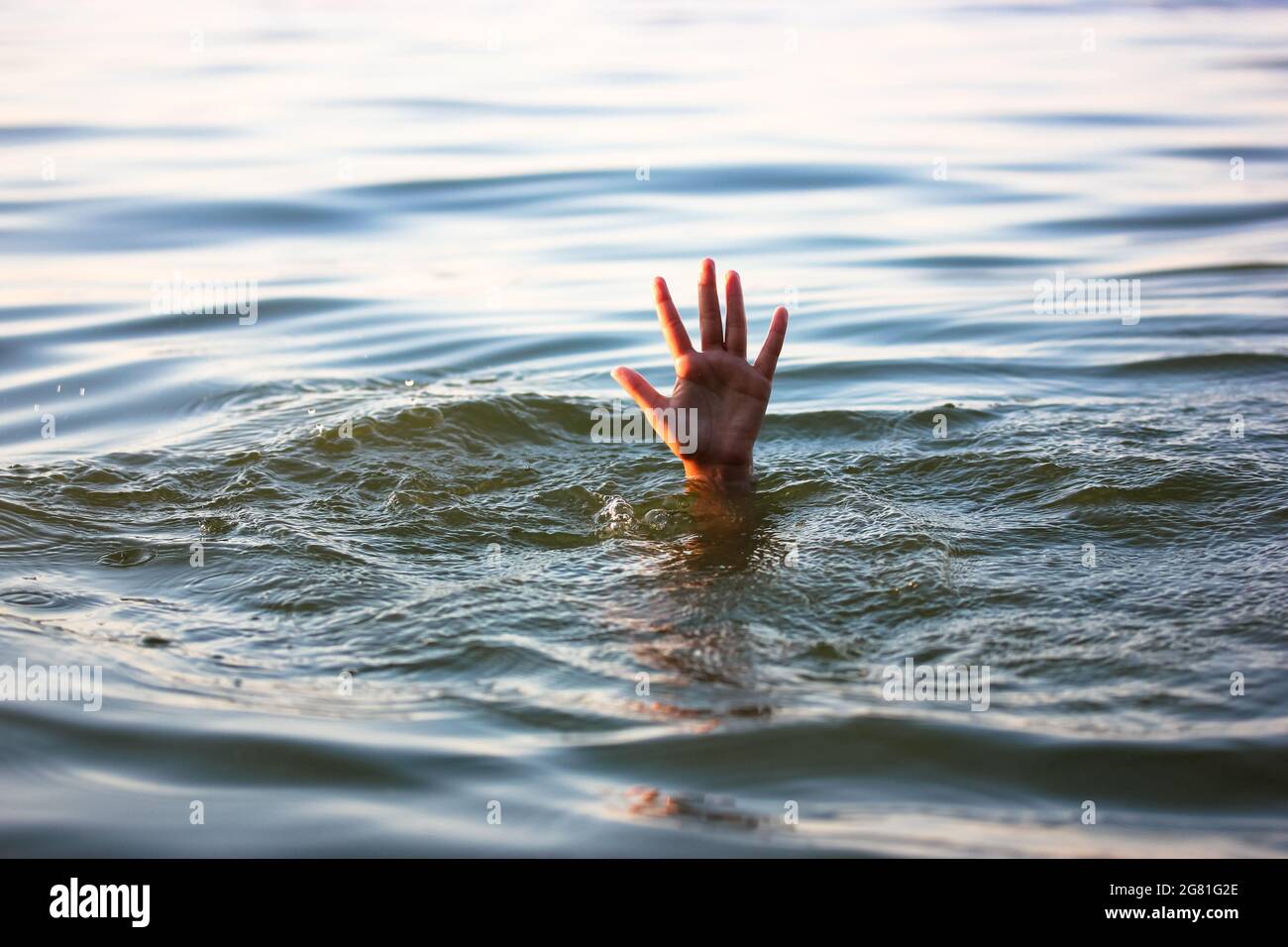 A man is drowning in water. A hand peeks out from under a water. A