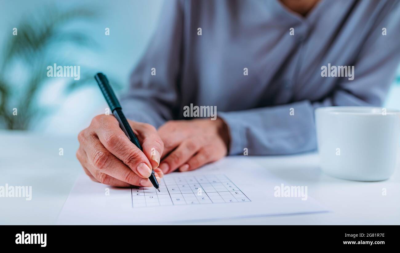 Senior woman solving sudoku puzzle Stock Photo