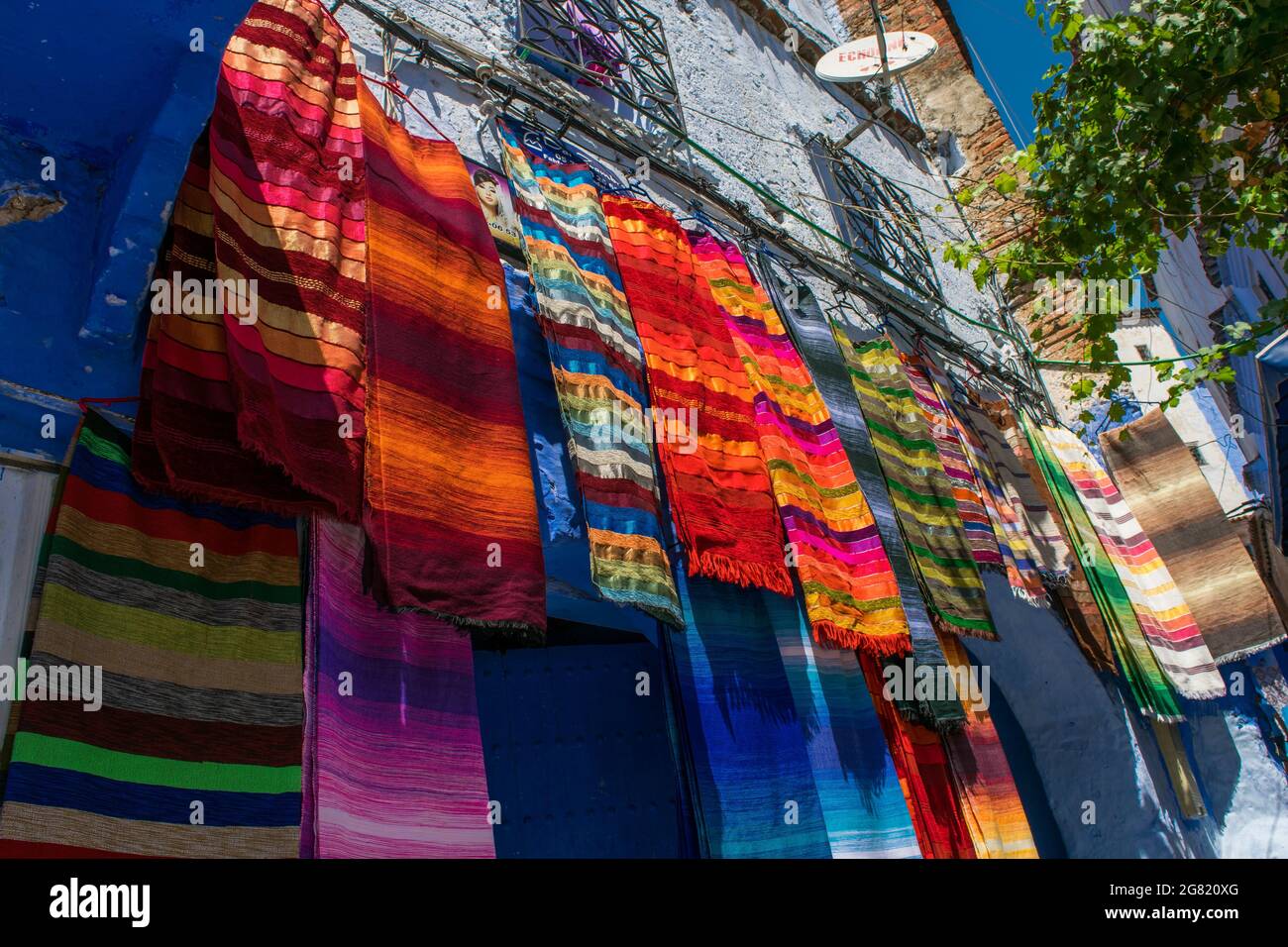 CHEFCHAOUEN, MOROCCO - Aug 31, 2018: The colorful fabrics and scarfs displayed in a narrow street in Chefchaouen town, Morocco Stock Photo