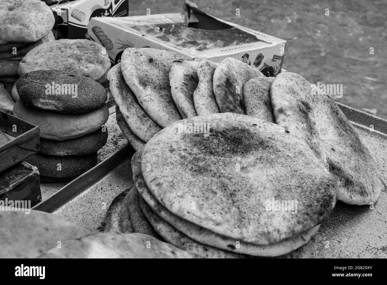 CHEFCHAOUEN, MOROCCO - Aug 31, 2018: A grayscale shot of hot flatbreads for sale in a market in narrow street of Chefchaouen town, Morocco Stock Photo