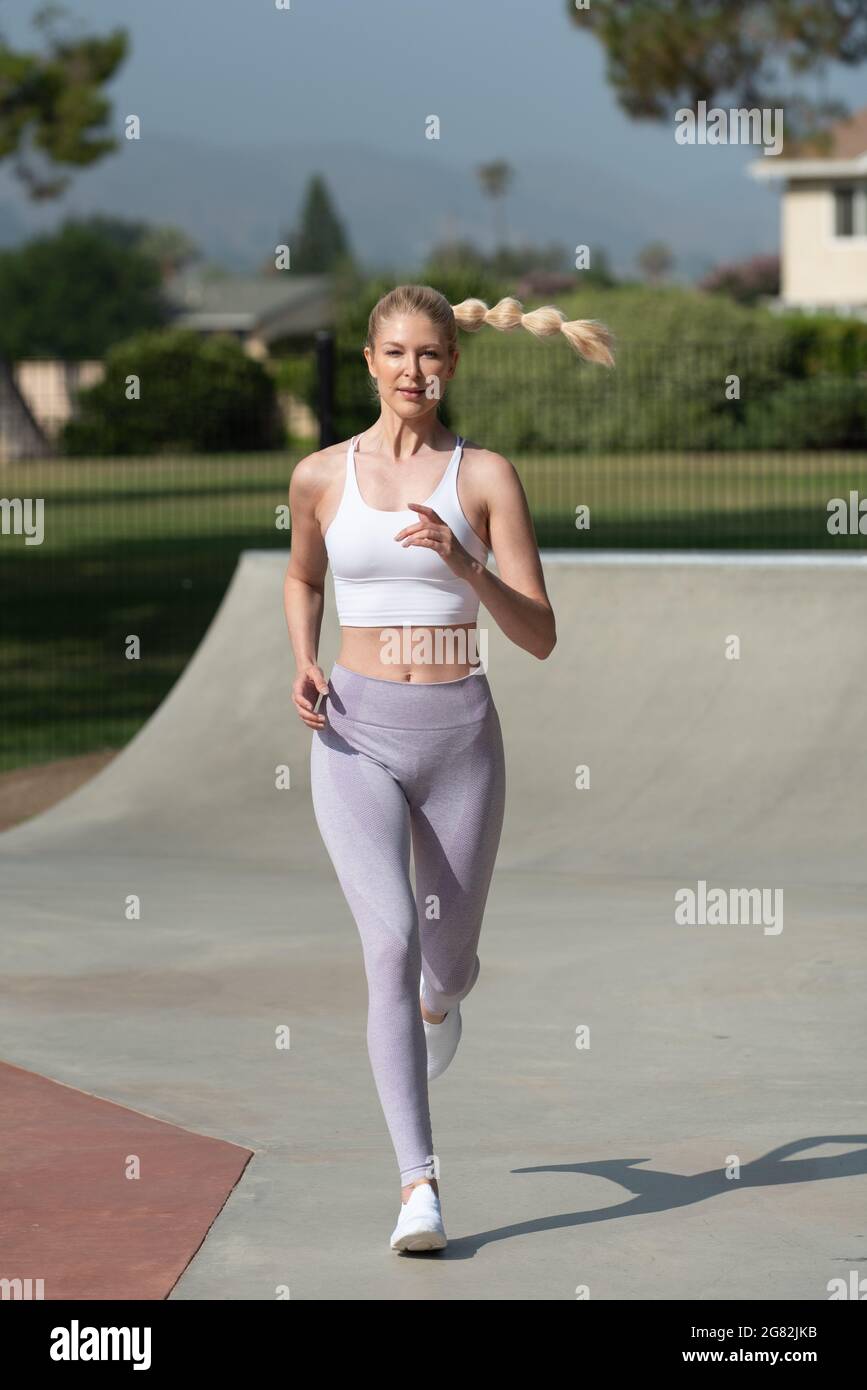 Healthy and fit atrractive blonde woman jogging for exercise in the park. Stock Photo