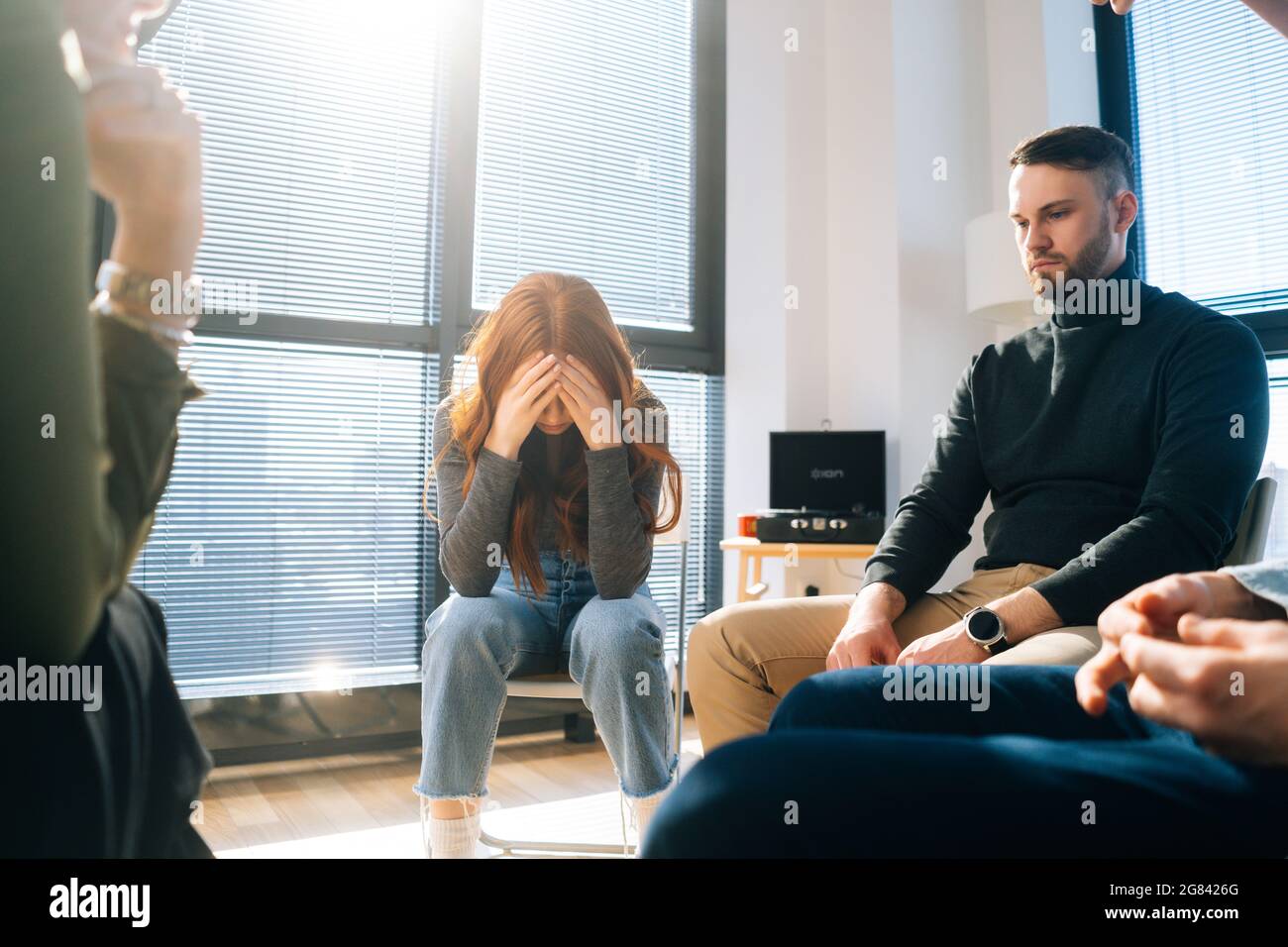 Front view of sad crying young woman sharing problem sitting in circle
