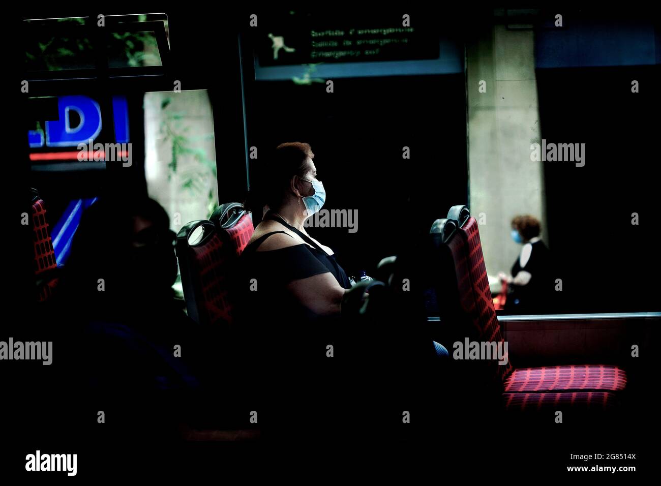 Masked woman looking out of bus window, Barcelona, Spain. Stock Photo