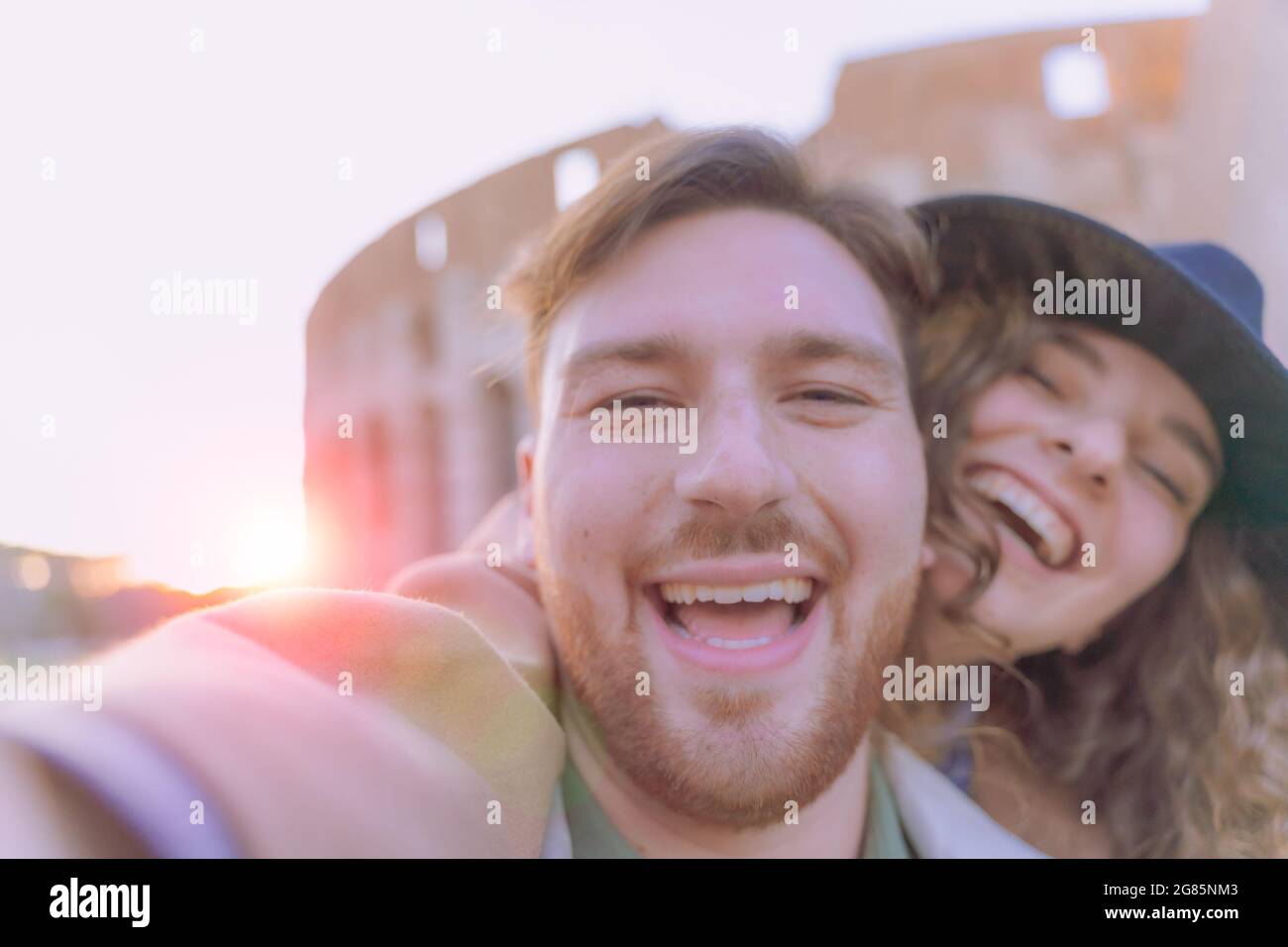 Young couple at the Colosseum, Rome. Happy tourists visiting italian famous landmarks and taking photo selfie portrait. Love, technology and travel co Stock Photo