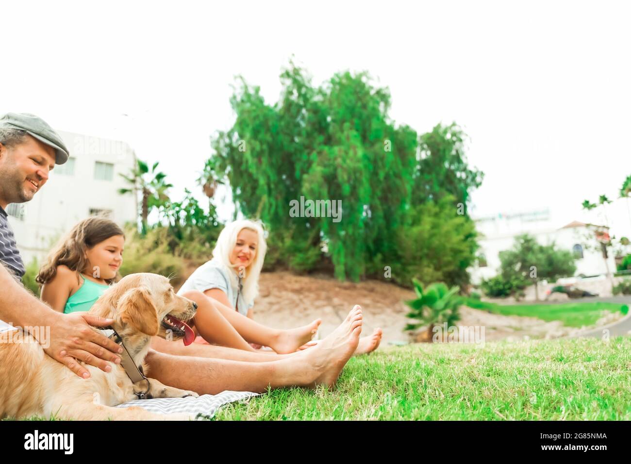 Family playing with the dog. beautiful day in the park. Happy family doing picnic in the nature outdoor. Focus the dog. Animal and love concept. Stock Photo