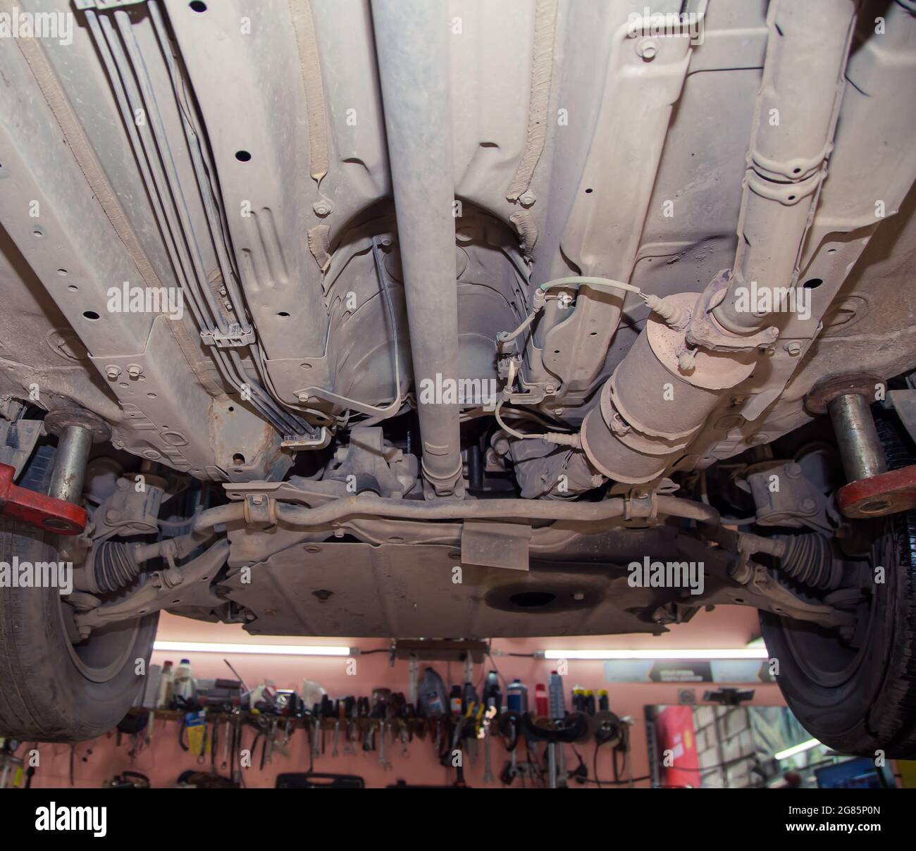 Bottom view of the underbody and wheels of an old car on a lift. In the ...