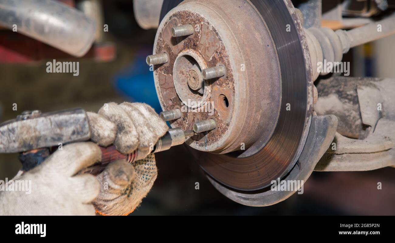 Gloved hands remove the rear rusted wheel hub. In the garage, a man changes  parts on a vehicle. Small business concept, car repair and maintenance  service. UHD 4K Stock Photo - Alamy