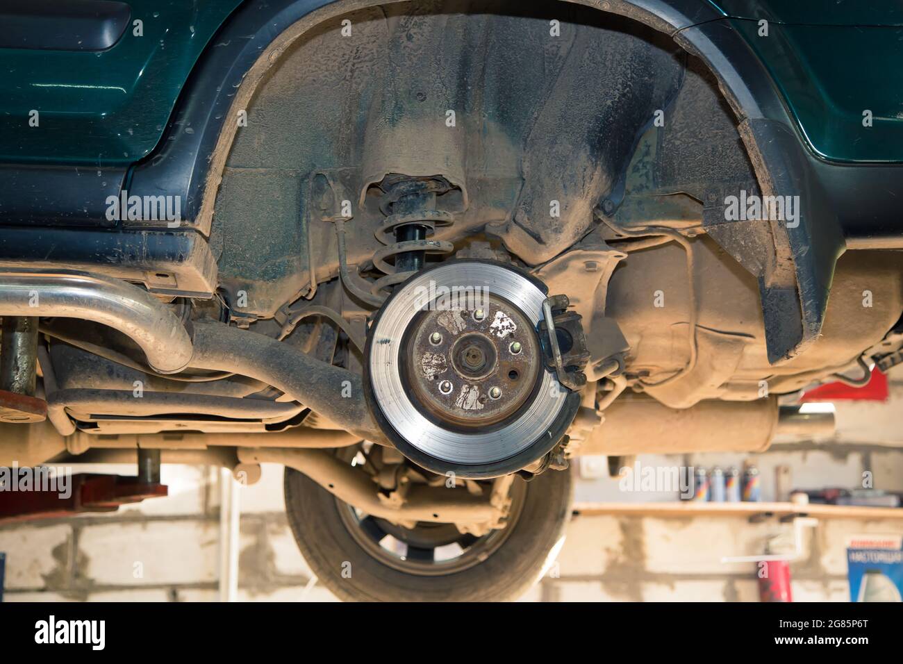 Rear wheel hub of a car lifted on a lift. In the garage, a man changes parts on a vehicle. Small business concept, car repair and maintenance service. UHD 4K. Stock Photo