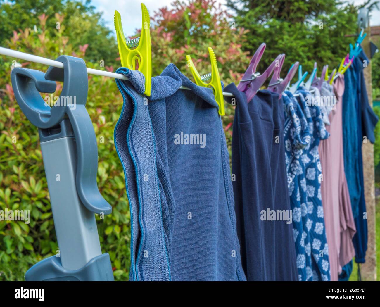 Closeup POV shot of a prop / pole hooked onto a washing line, with pegged clothes  hanging to dry, with bushes in the background Stock Photo - Alamy