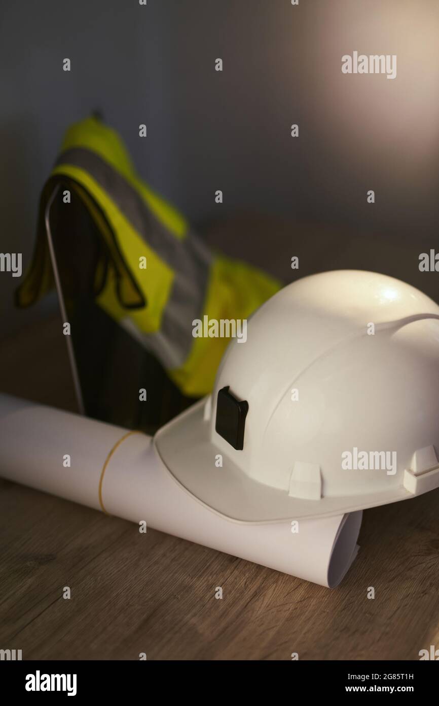 Architect table concept: white safety helmet, rolled blueprints, laptop computer and safety reflective vest. Construction, design, architecture or building industry concept. High quality photo Stock Photo