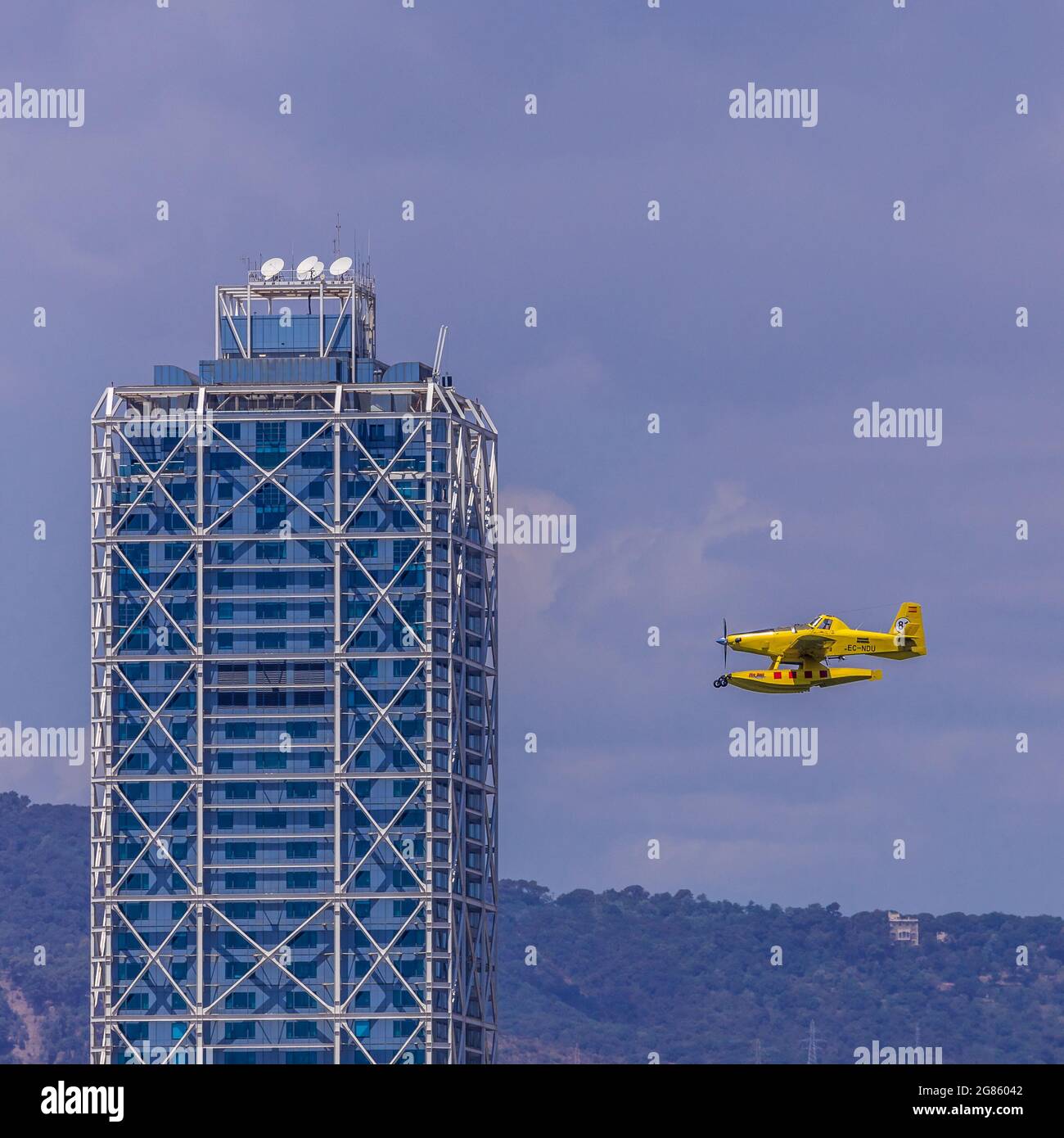Yellow plane flying under a building Barcelona, July 17, 2021 Stock Photo