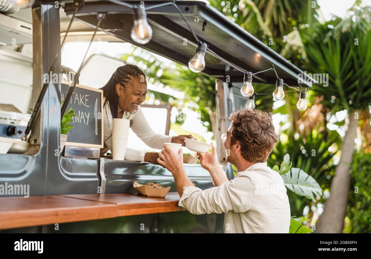 Afro food truck owner serving meal to male customer - Modern business and take away concept Stock Photo