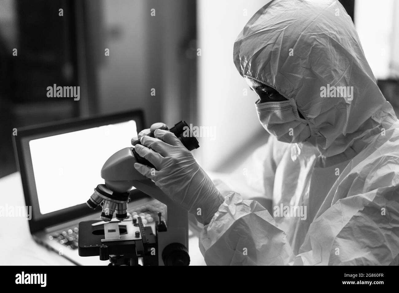 Female scientist working in research lab examining microorganisms through microscope - Science and technology concept Stock Photo