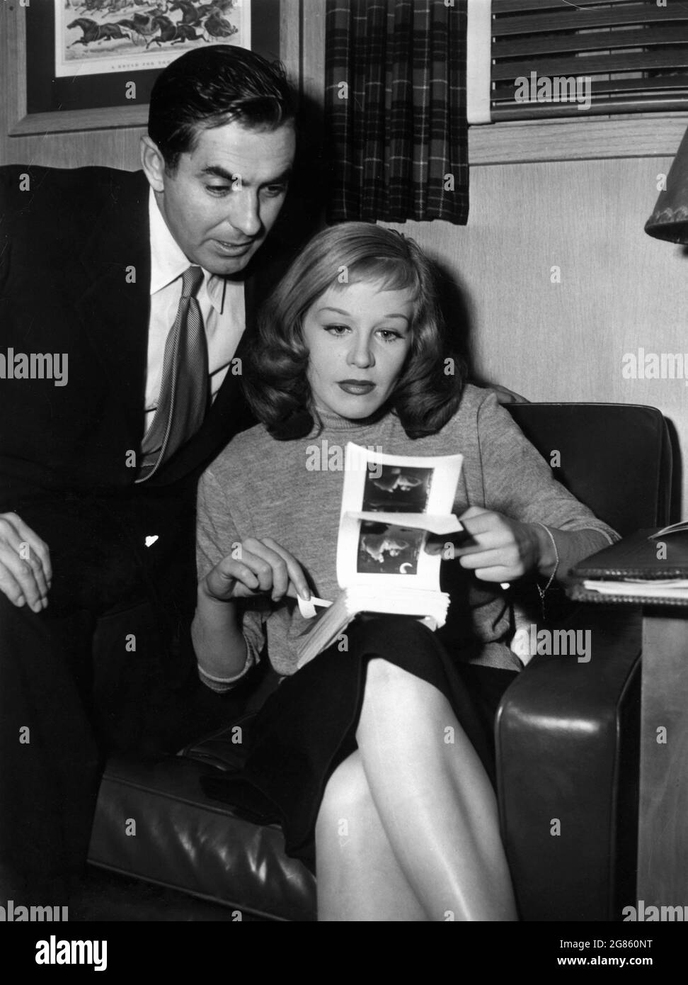 TYRONE POWER and HILDEGARD KNEF on set candid checking proof contact prints of publicity stills during filming of DIPLOMATIC COURIER 1952 director HENRY HATHAWAY from novel Sinister Errand by Peter Cheyney Twentieth Century Fox Stock Photo