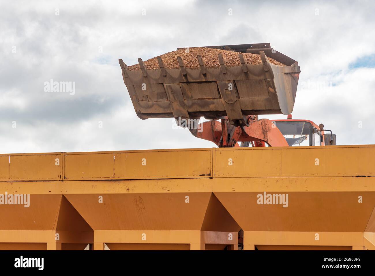 Bucket of an excavator pouring sand into silos. Stock Photo