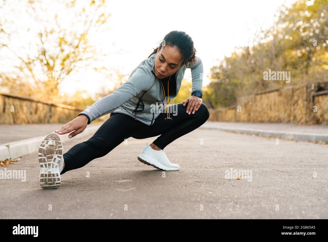 Focused african american sportswoman stretching her leg while working ...