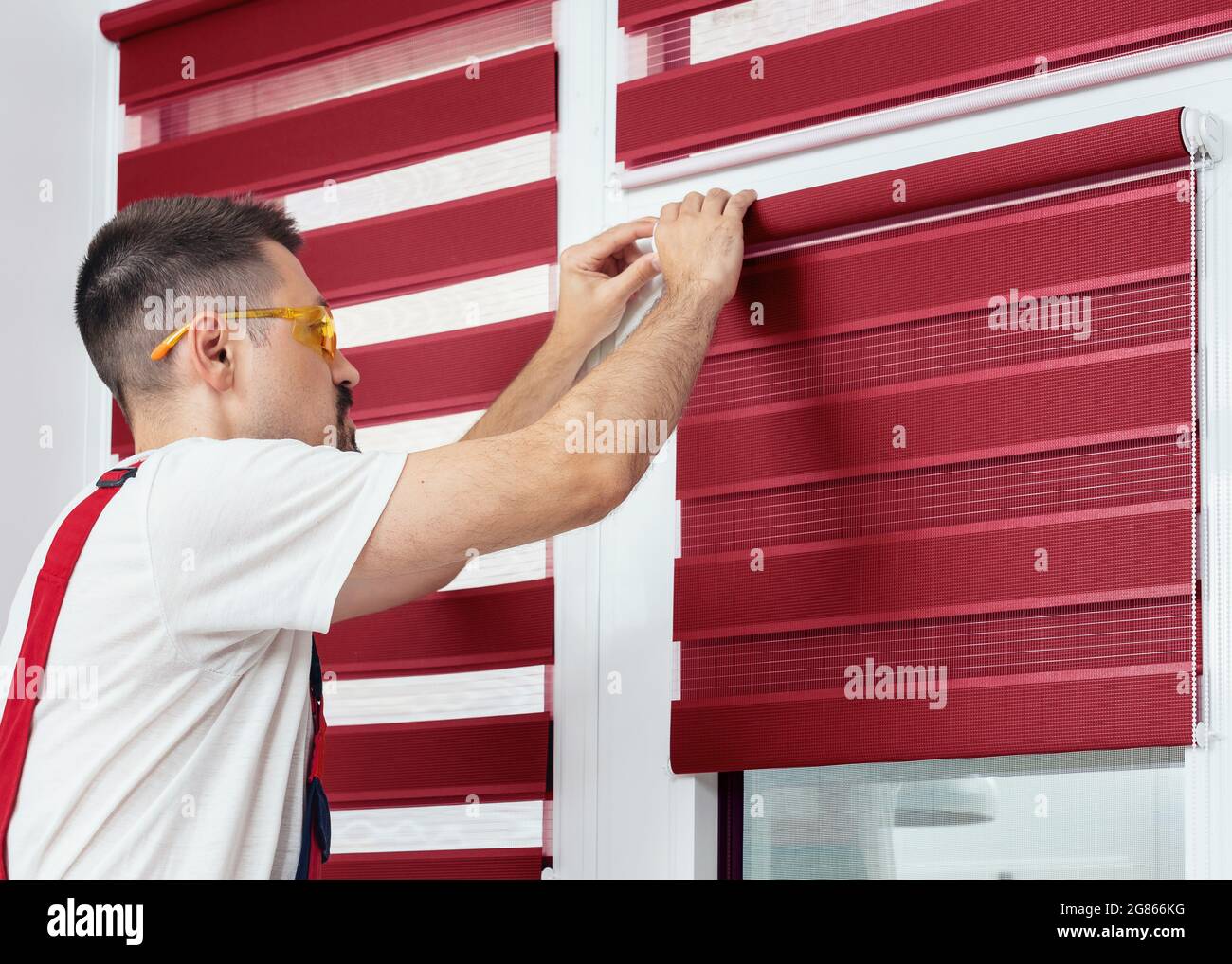 Mounting shutters, man installing fabric blinds. Handyman installing a part of roller window