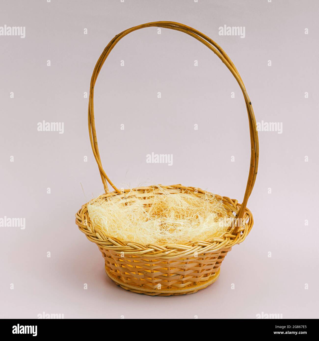An empty wicker basket of yellow color with a round handle stands on a ...