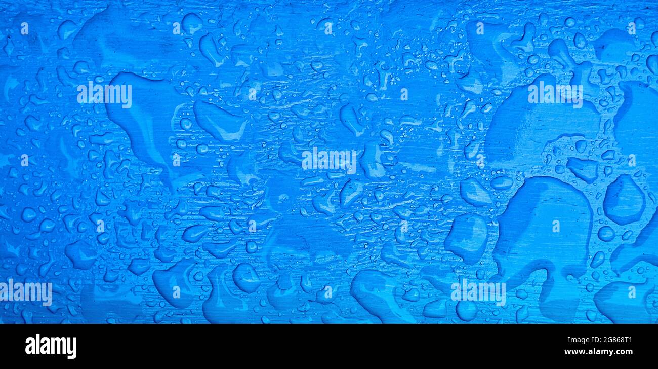 Pure drops of water on the blue surface. Banner for water company. Raindrops or dew. Stock Photo