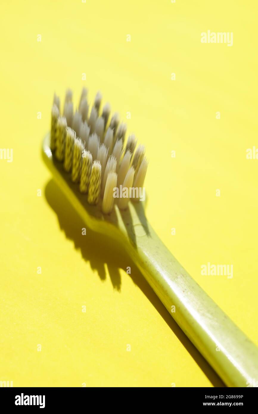 Green plastic toothbrush on sunny yellow table. Stock Photo