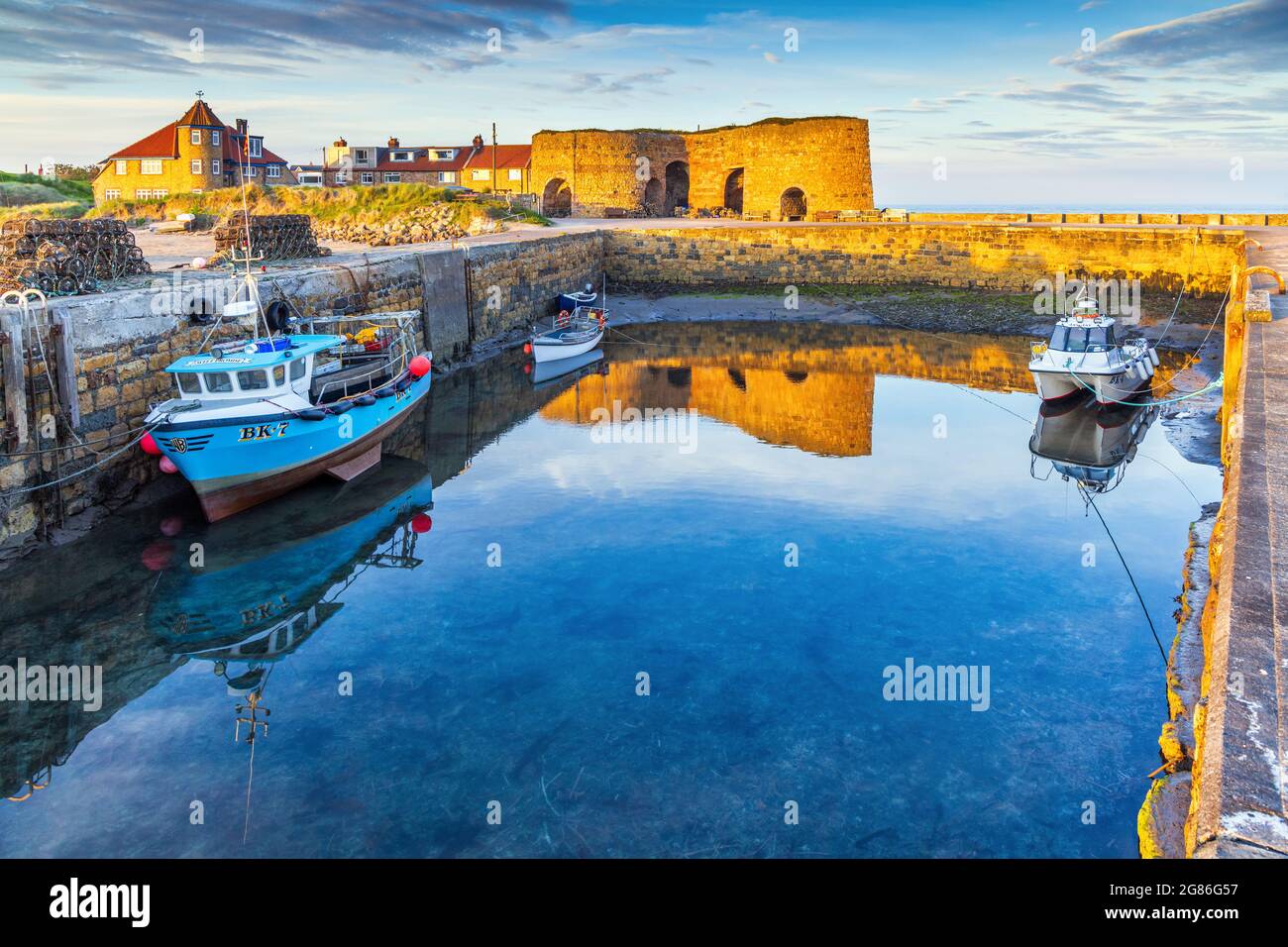 The evening sun lights up the harbour and the old lime kilns at Beadnell, the only west-facing harbour on Northumberland's coast. Stock Photo