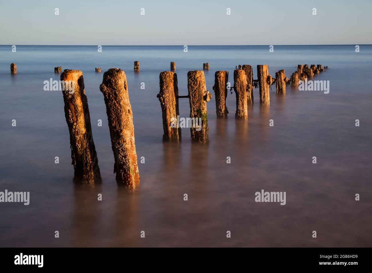 Old groynes surrounded by a rising sea on an incoming tide Stock Photo