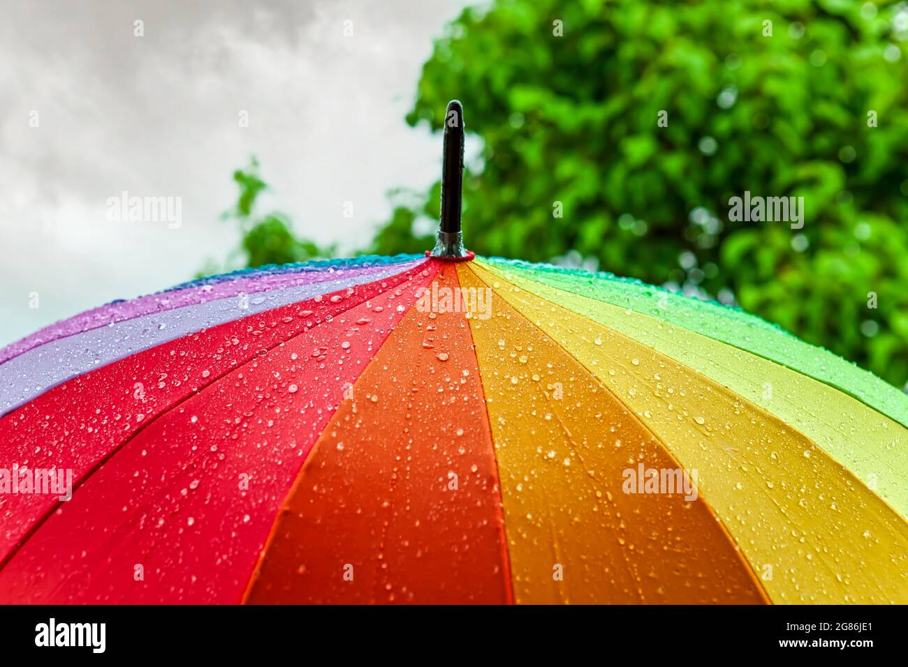 Rain On Rainbow Umbrella. Umbrella under heavy rain against cloudy sky