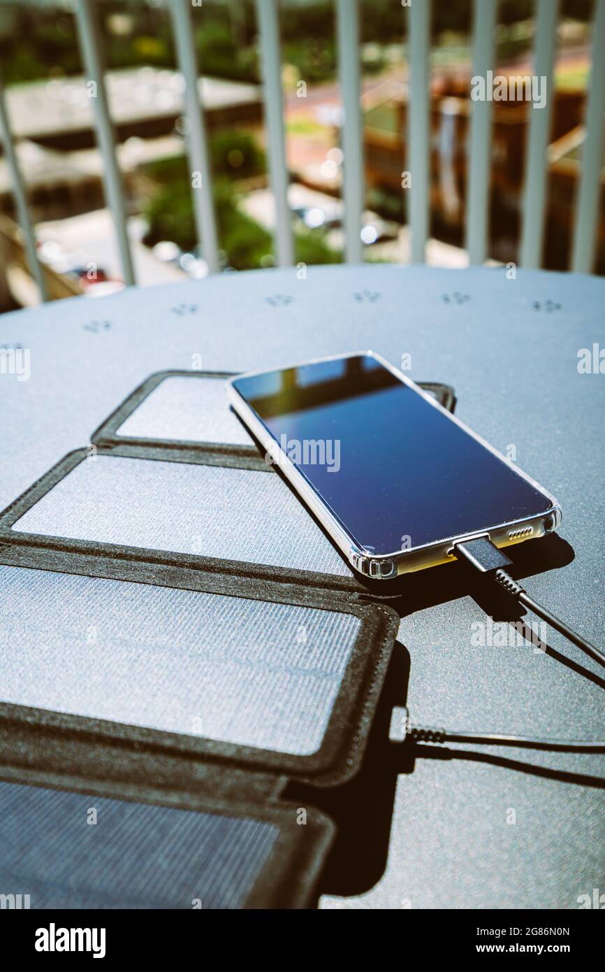 Charging a smartphone from home with a portable solar panel charger ...
