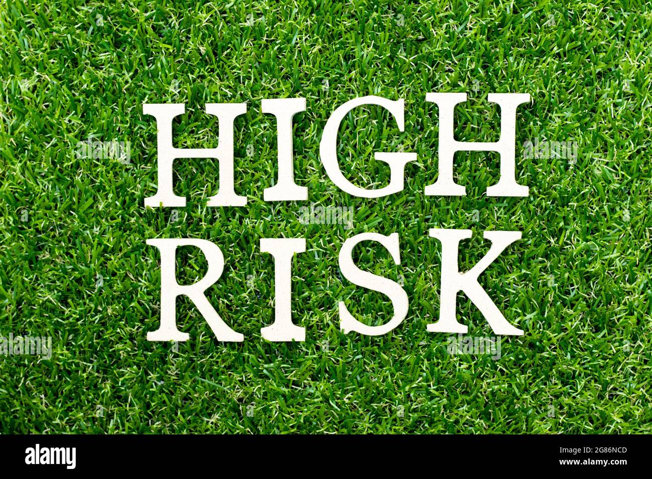 Wood alphabet letter in word high risk on green grass background Stock ...