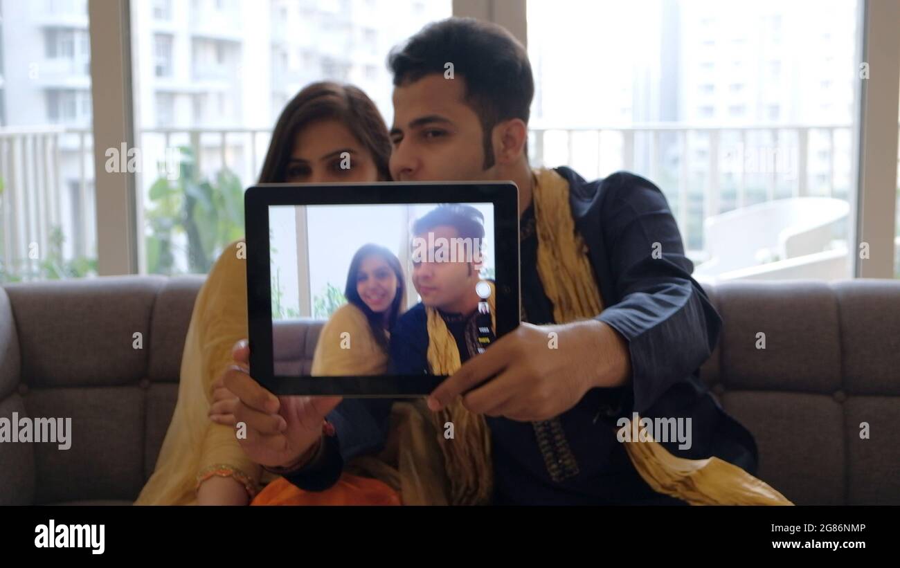 Closeup shot of a South Asian couple taking a selfie with a tablet ...