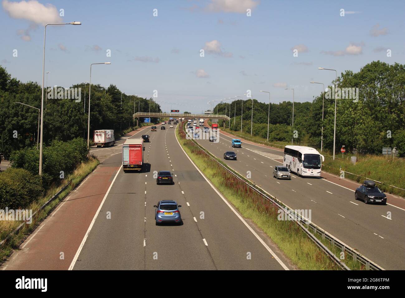M6 motorway traffic with bright blue sky and bridge in distance Stock Photo