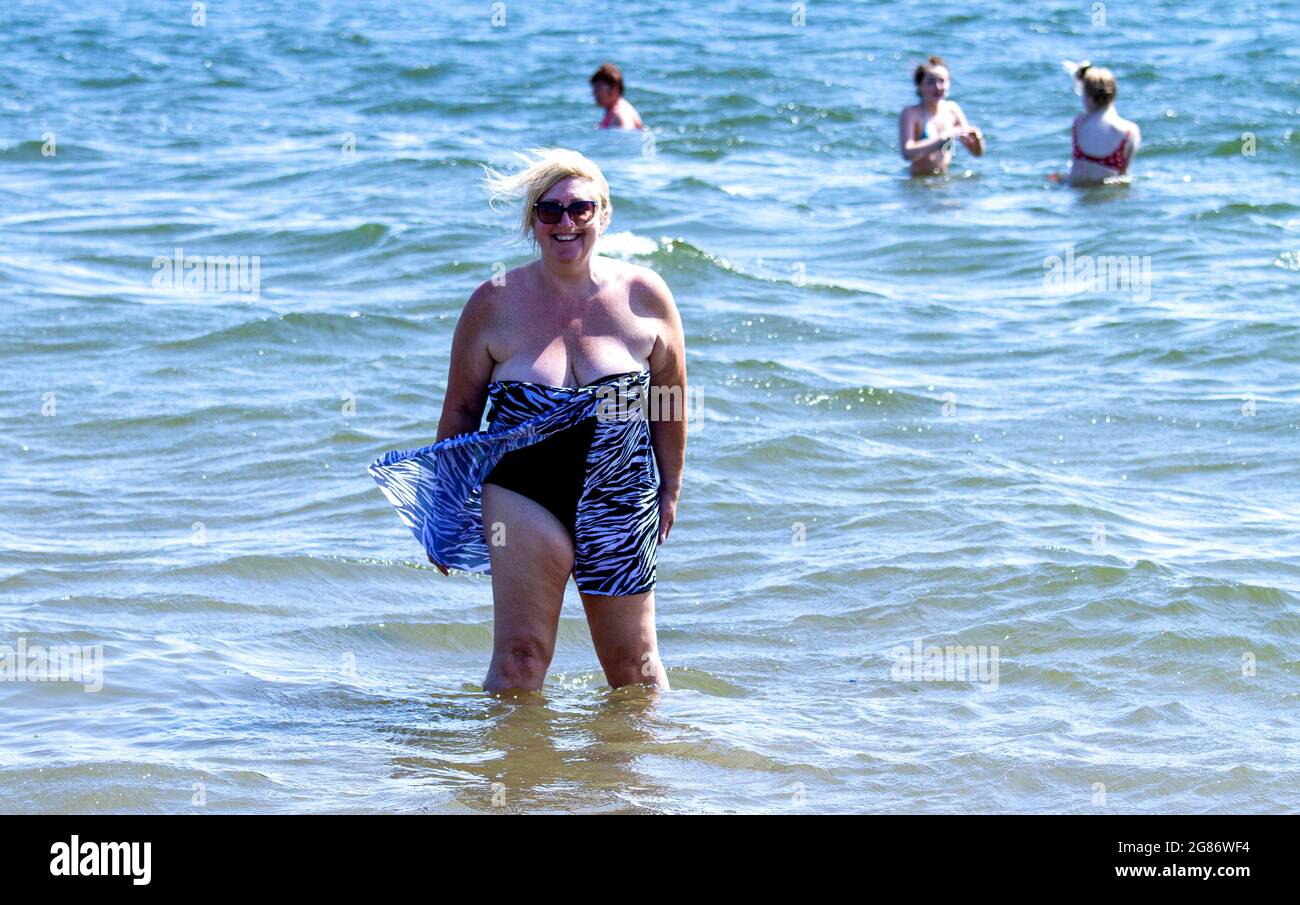 Dundee, Tayside, Scotland, UK. 17th July, 2021. UK Weather: July heatwave sweeping across North East Scotland with maximum temperature 27°C. Beach-goers day out at Broughty Ferry beach in Dundee. A local senior woman enjoying the warm summer sunshine cooling down in the river Tay. Credit: Dundee Photographics/Alamy Live News Stock Photo