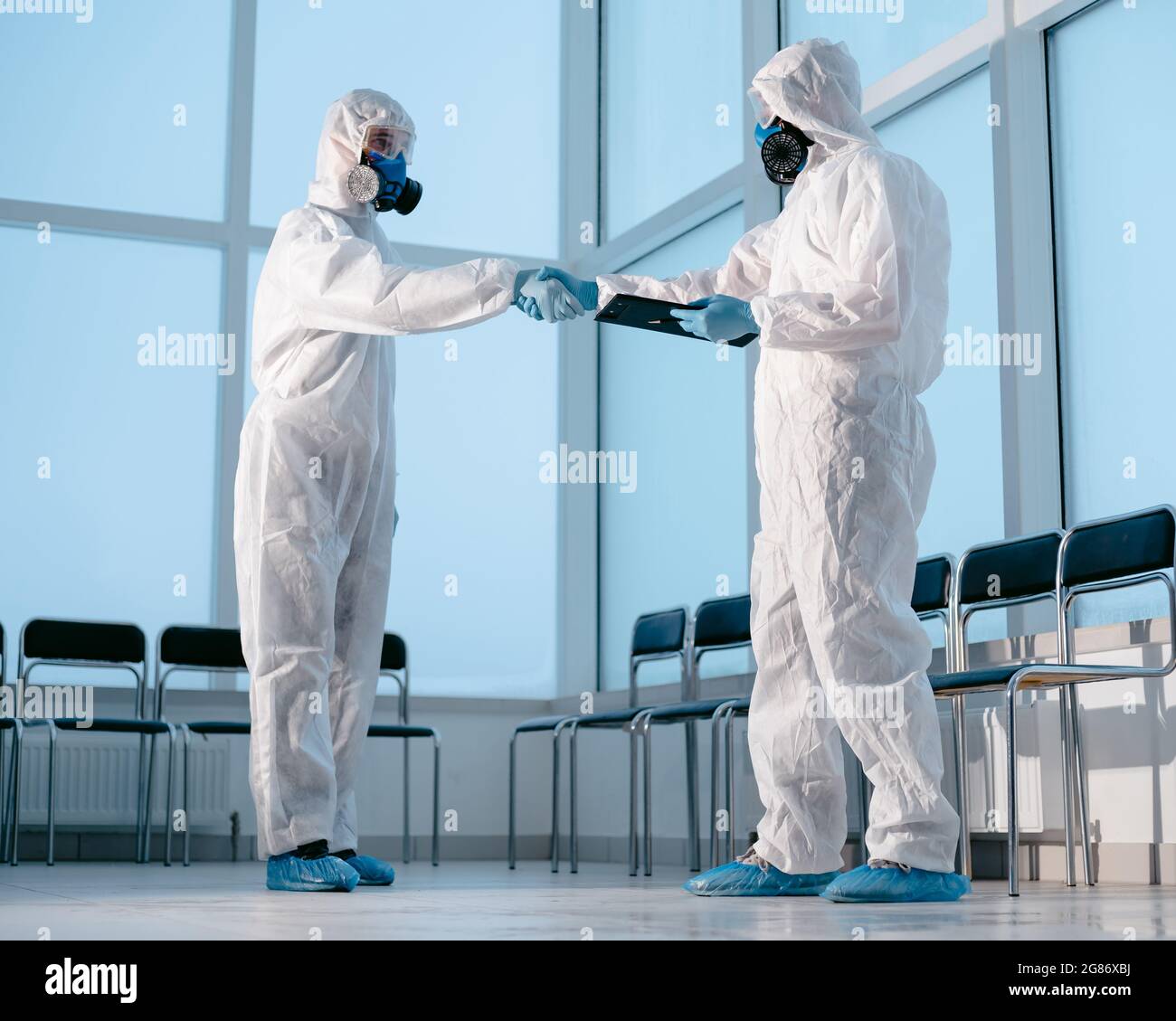 lab technicians in protective suits shaking hands. Stock Photo