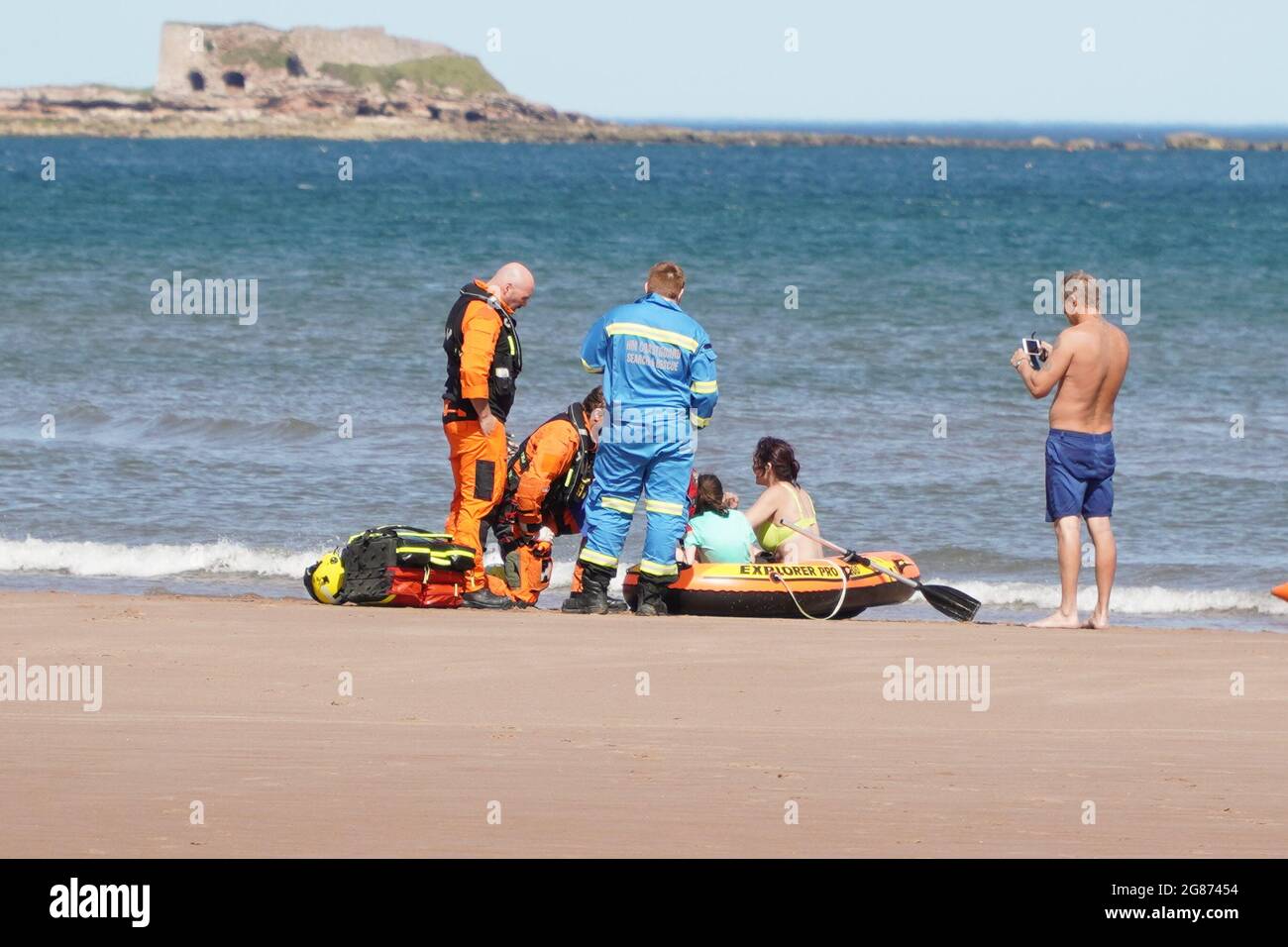 Lunan Bay Beach, Angus, Scotland, UK, 17th of July 2021: Major rescue operation carried out by the coastguard and RNLI, after a mum and daughter drifted out to sea on their inflatable dinghy in strong winds today at Lunan Bay Beach. An offshore supply vessel, which was nearby, also launched it FRC to assist with the rescue. In this photo you can see helicopter crew speaking with the Mum and Daughter, as they sit in their inflatable dinghy. (Credit:Barry Nixon/Alamy live news) Stock Photo