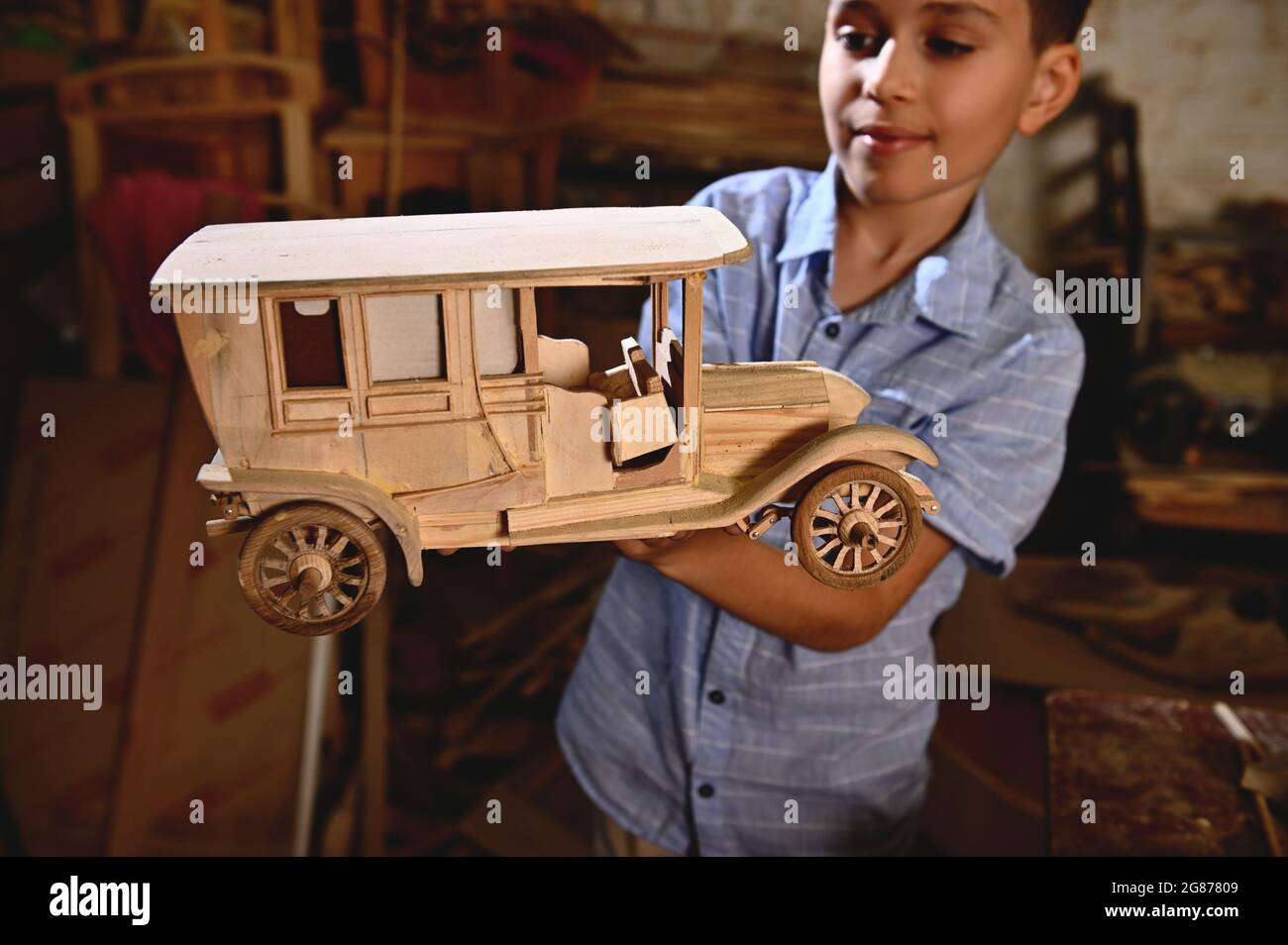 Adorable schoolboy holding a wooden model of handmade car