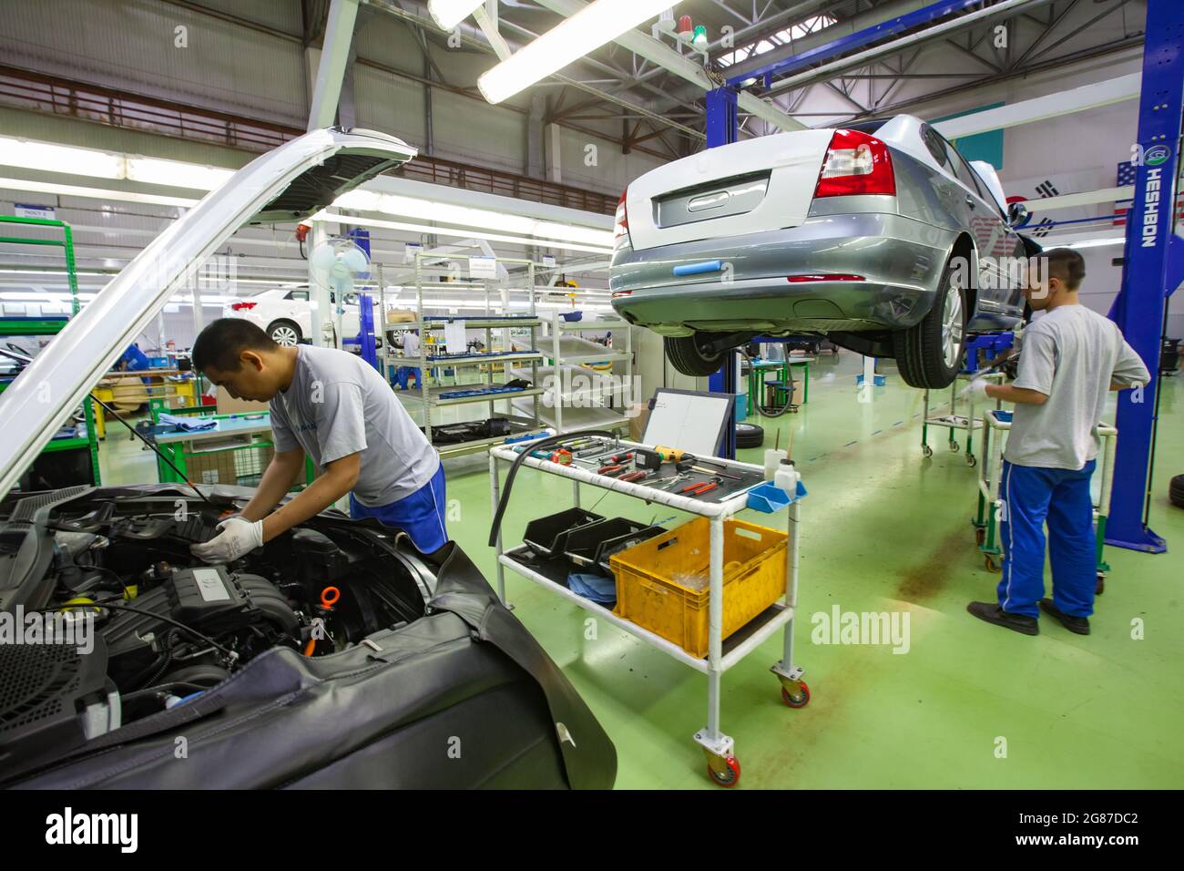 Ust'-Kamenogorsk,Kazakhstan,May 31,2012: Asia-Auto company auto-building plant. KIA cars assembling. Worker (left) install engine parts. Stock Photo