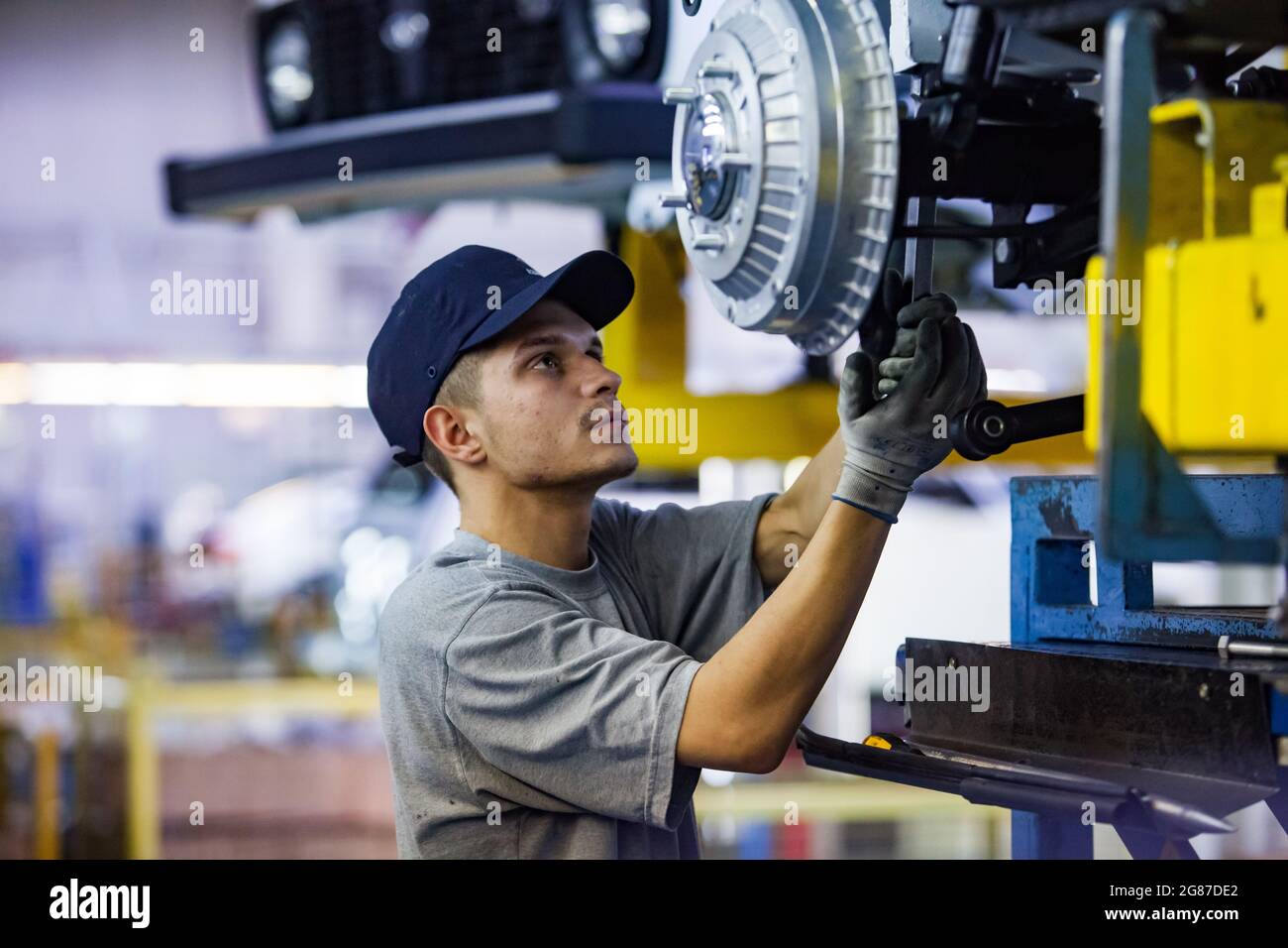 Ust'-Kamenogorsk, Kazakhstan - May 31,2012: Asia-Auto company auto-building plant. Young caucasian worker assembling car suspension and wheel hub. Stock Photo