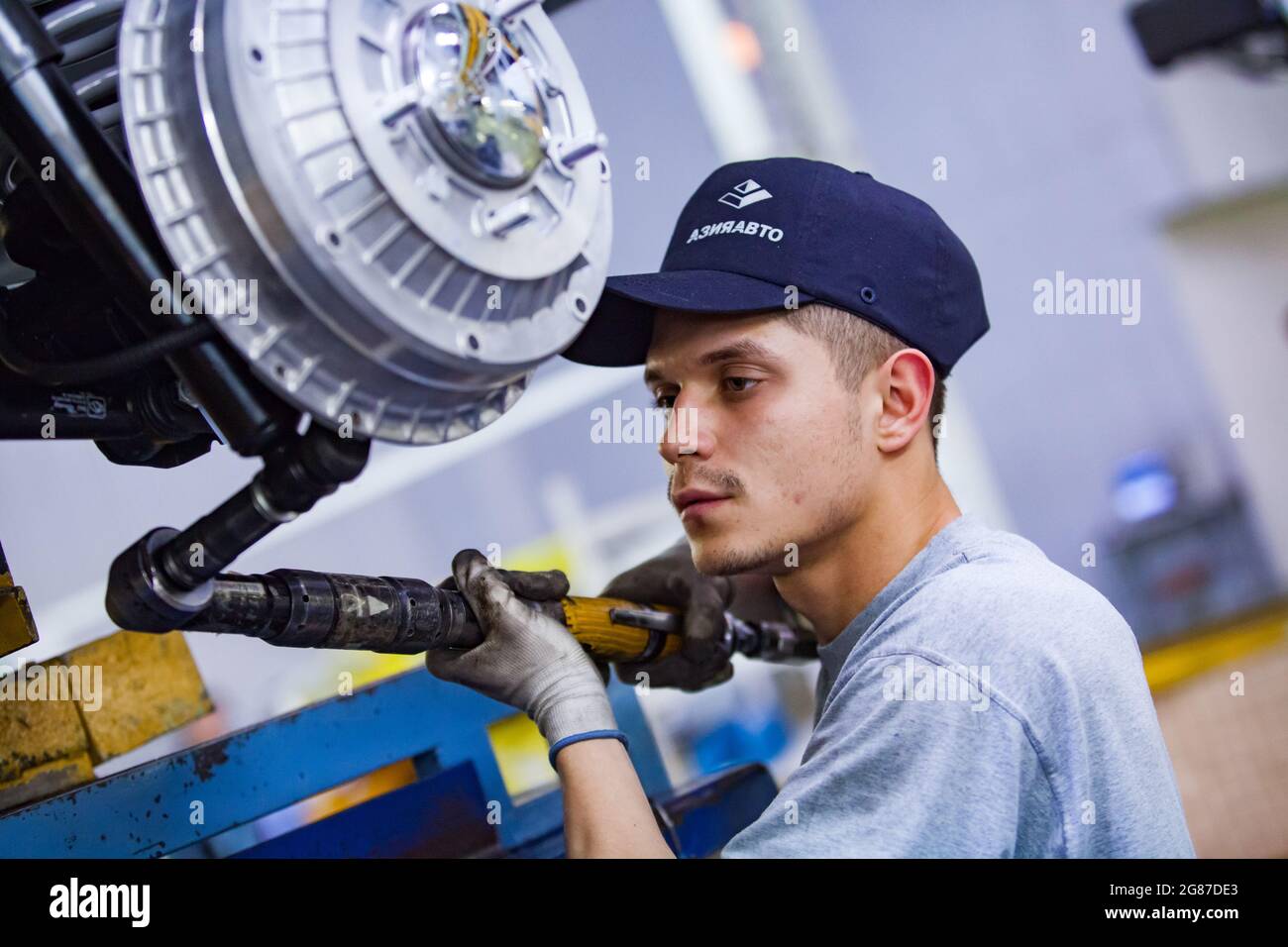 Ust'-Kamenogorsk,Kazakhstan,May31,2012:Asia-Auto company building plant.Worker assembling wheel hub and car suspension.Using pneumatic wrench tool. Stock Photo