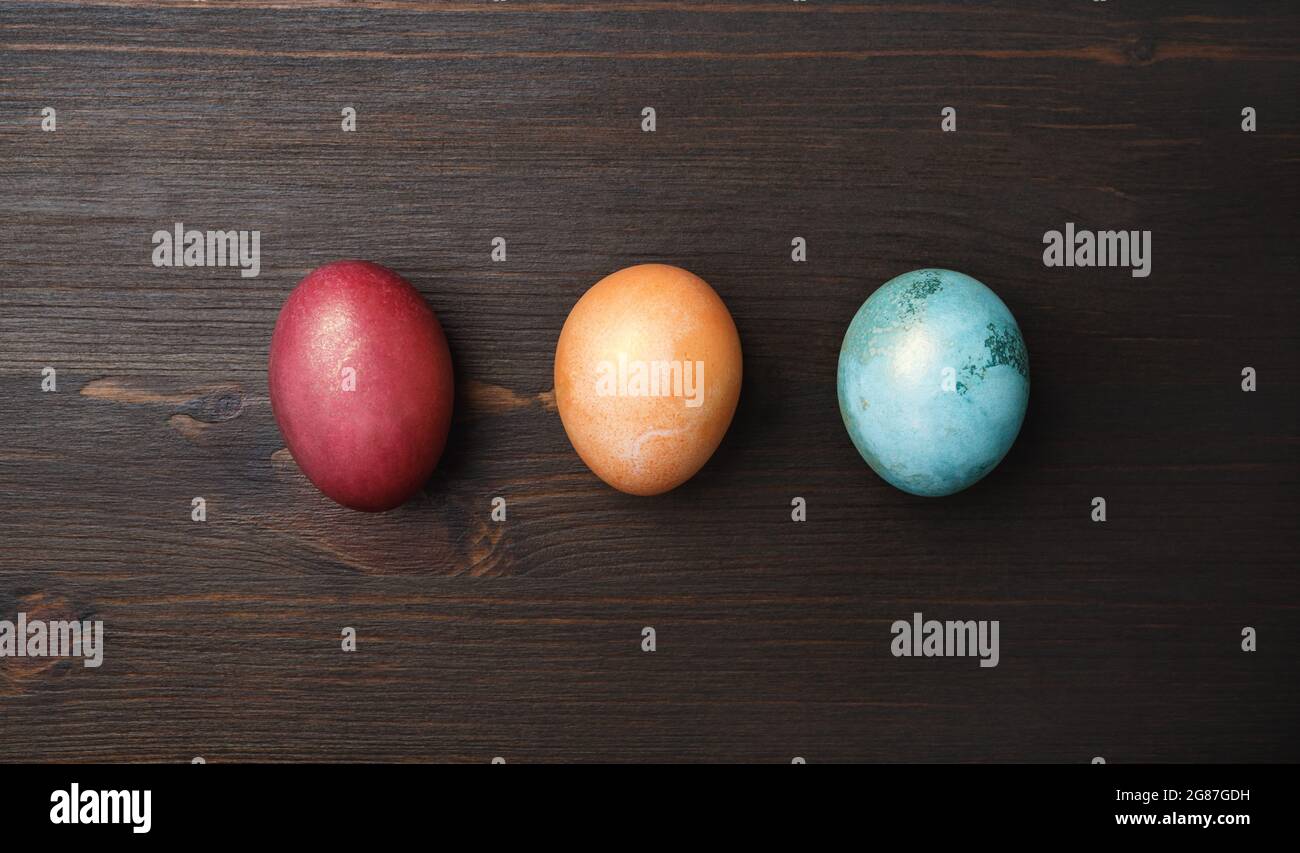 Three Easter eggs on wood table background. Flat lay. Stock Photo